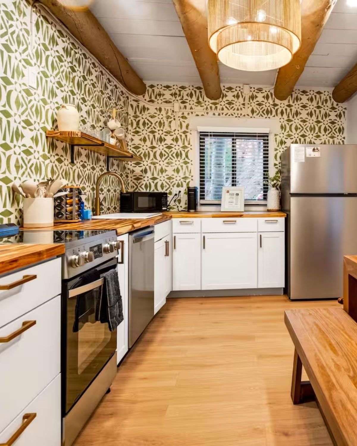 A full casita kitchen: a range and dishwasher, butcher block worktops, a full-height refrigerator and green patterned tile to the ceiling