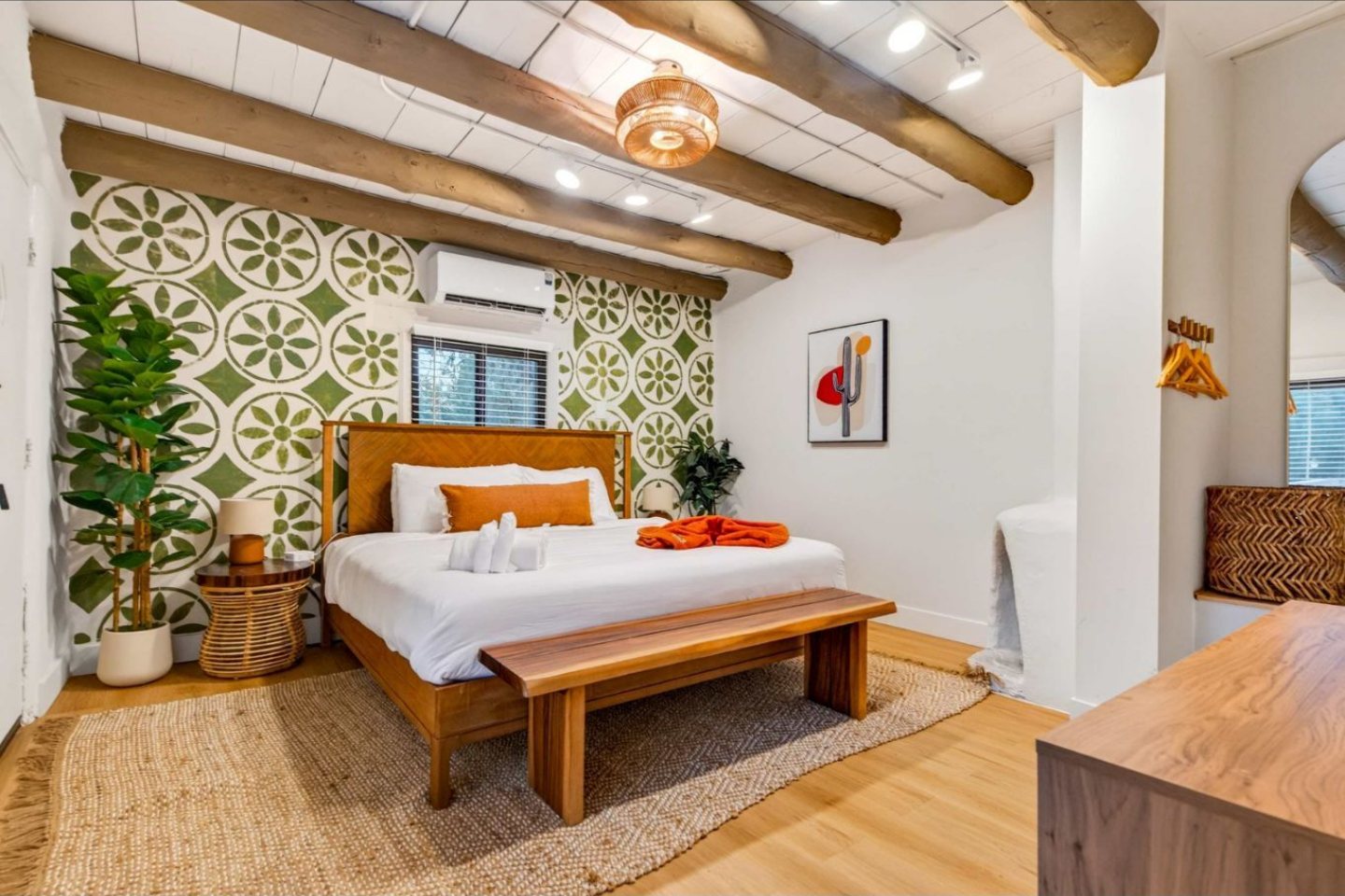 A restored casita bedroom with a wooden bed, green tilework feature wall and morning light