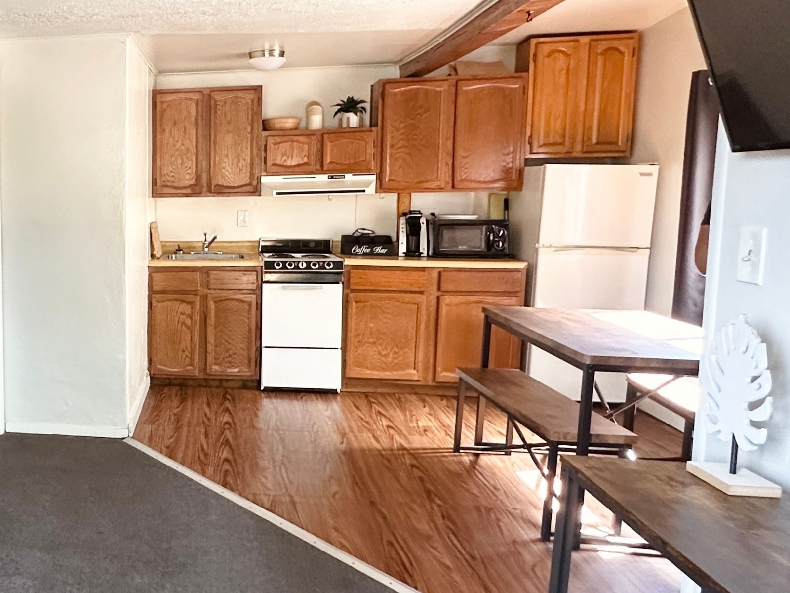 A casita kitchen before restoration: dark oak raised-panel cabinets, laminate worktops, a small enamel range and a vinyl floor